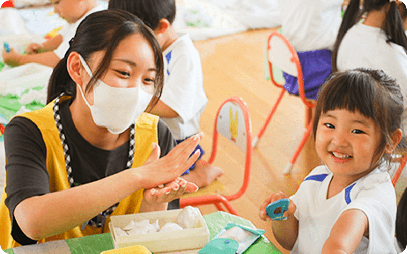 先生と粘土で遊ぶ女の子の画像